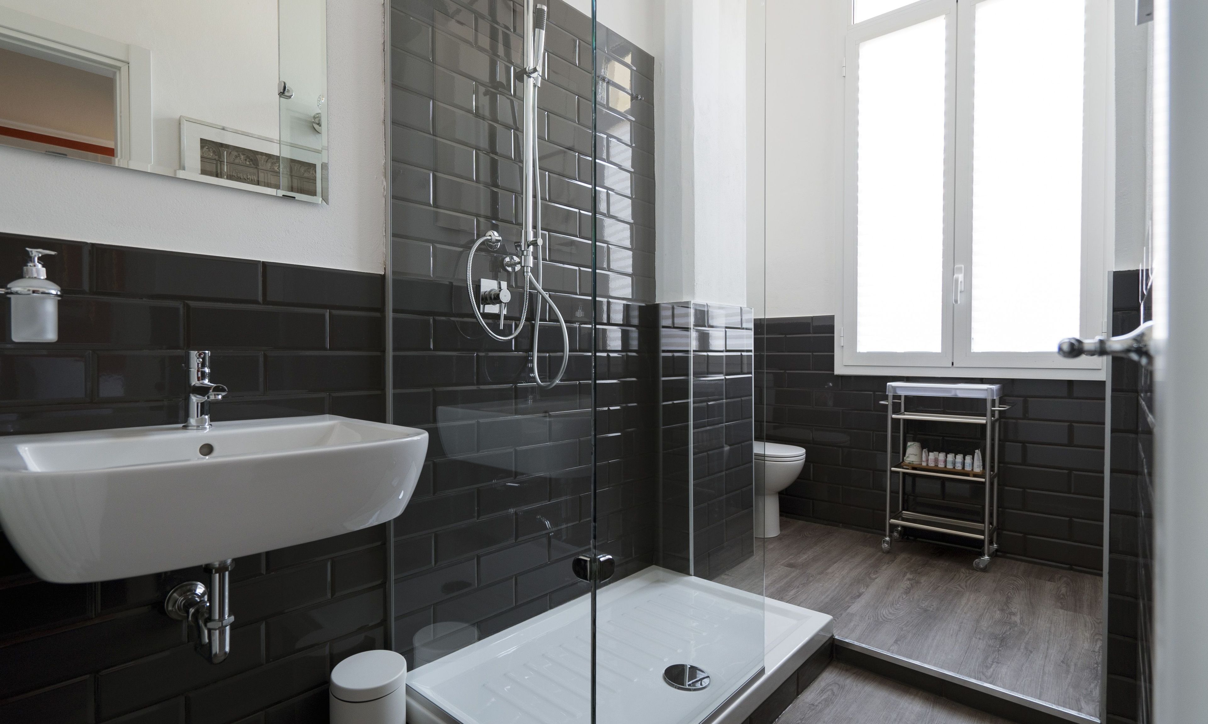 Et moderne badeværelse med et glasafskærmet brusebad, en hvid vask og et toilet.