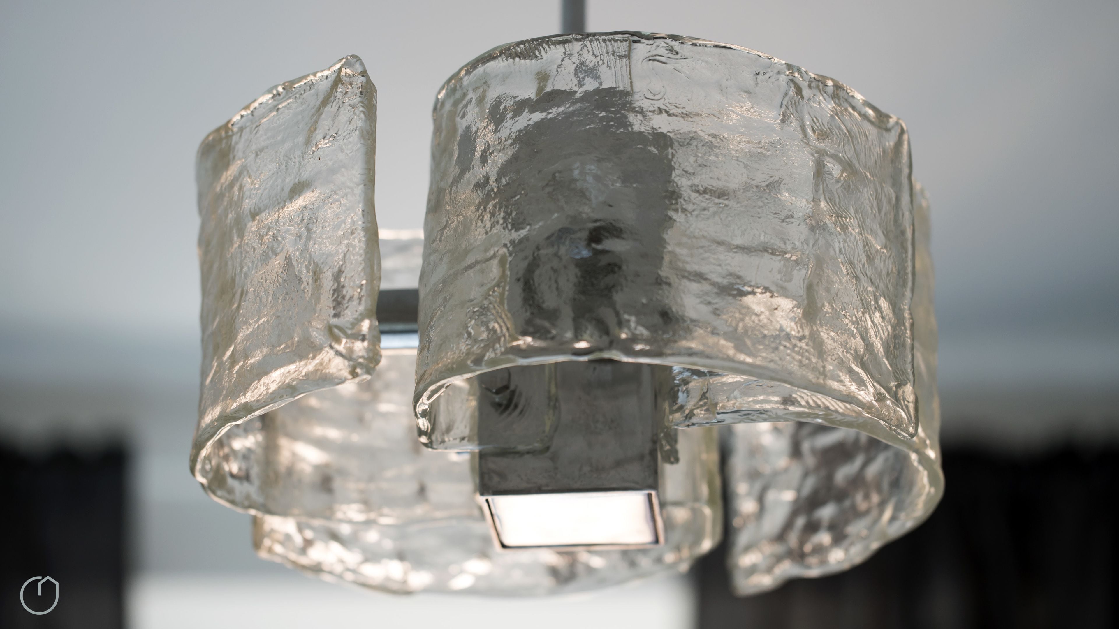 Un luminaire métallique à la texture particulière, doté d’une base carrée.