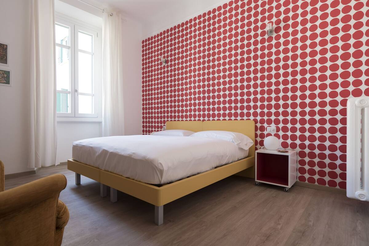 A bedroom with a bed, a nightstand, a chair, and a window.