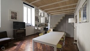 A modern kitchen with white cabinets, a dining area with a white table and chairs, and a staircase leading to another level.