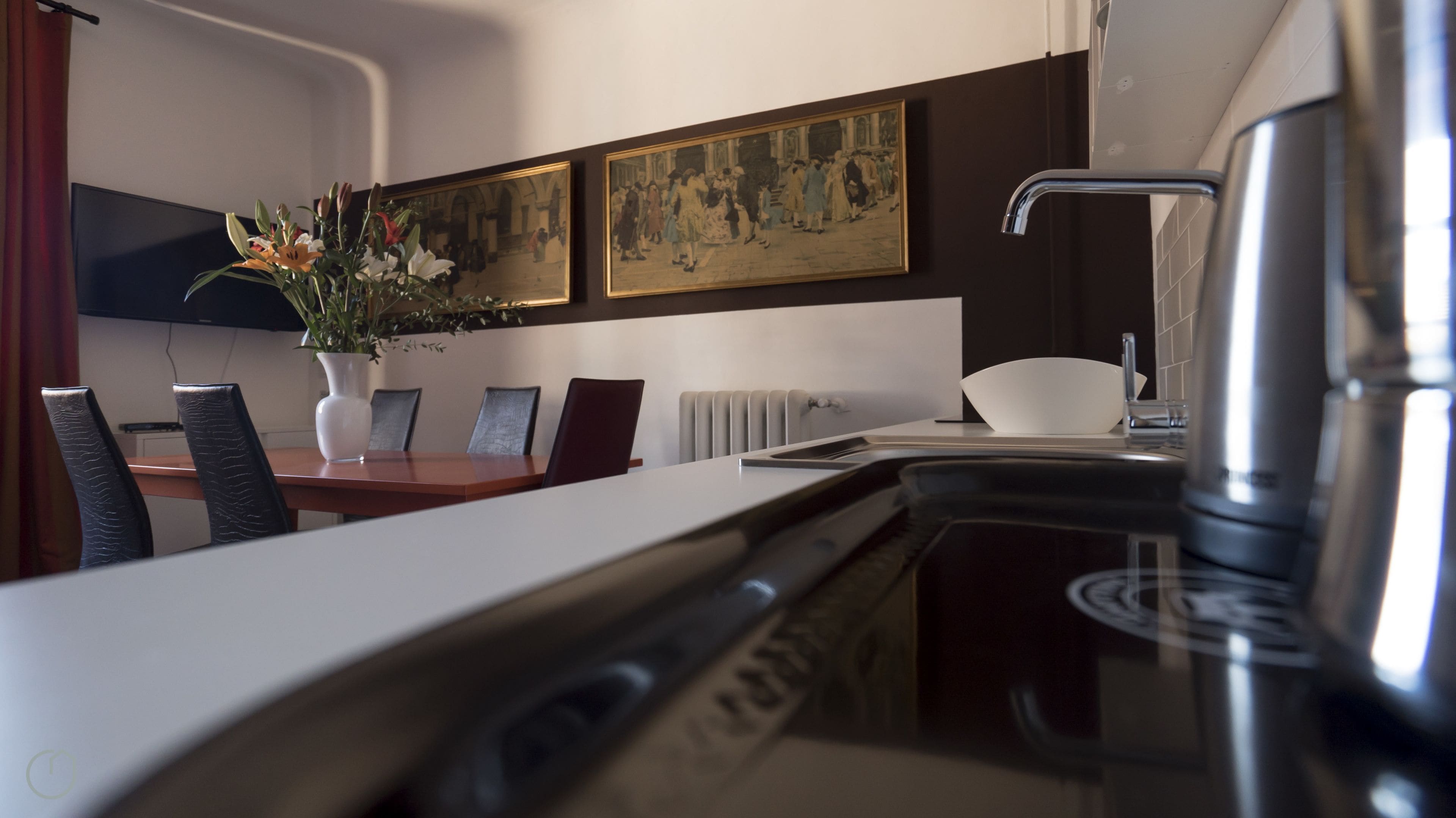 A modern kitchen with a dining area, a coffee machine, and a painting on the wall.
