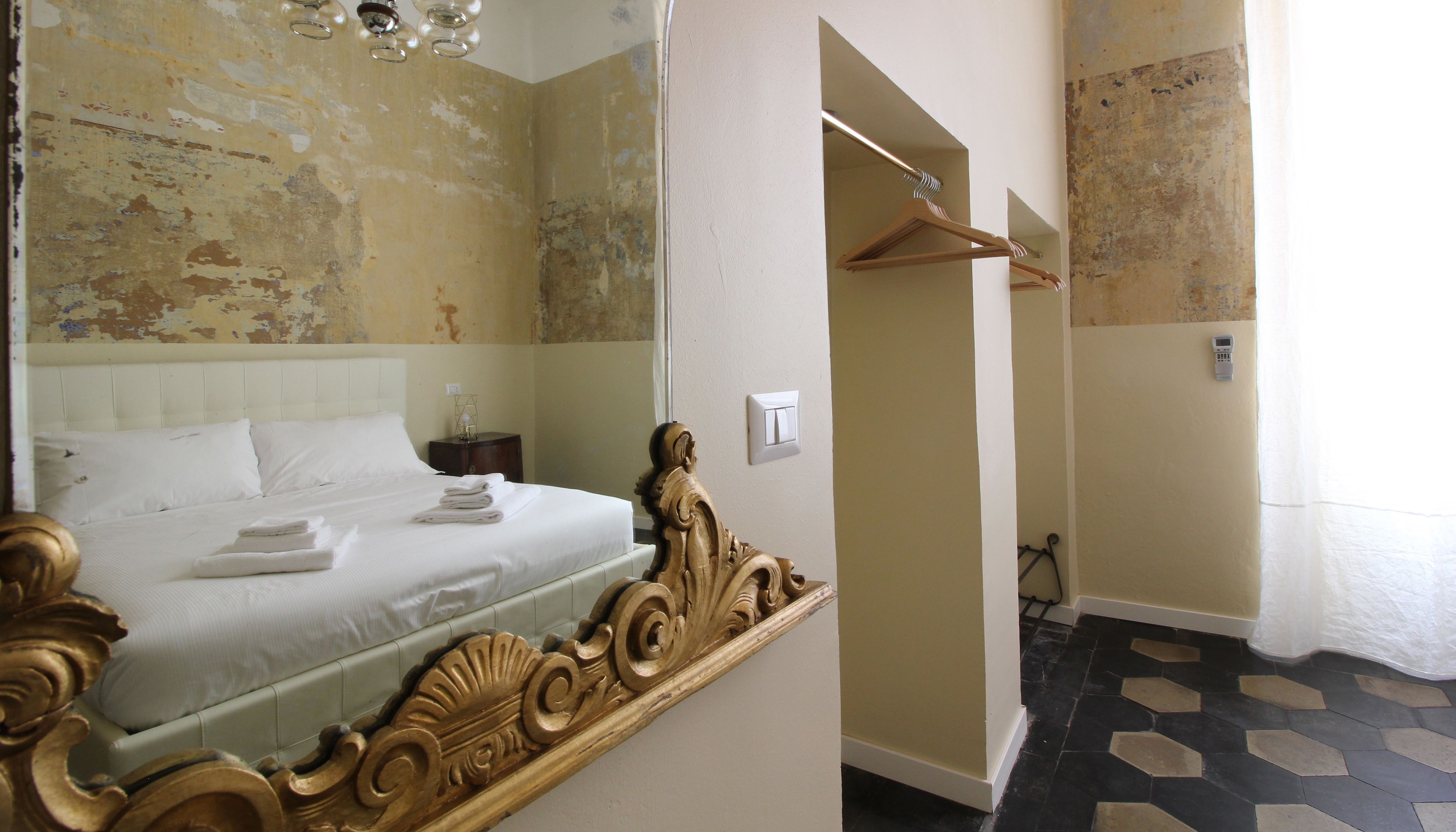 A hotel room with a large bed, a wooden headboard, a bedside table with a lamp, and a mirror.