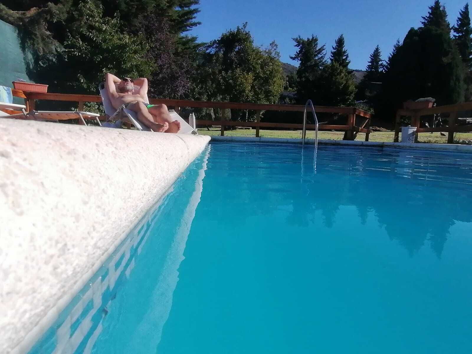 A swimming pool with a wooden deck and a wooden fence in the background.