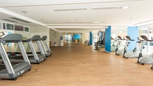 A spacious gym with treadmills and stationary bikes, wooden floors, and large windows. - Beach Class - MeuLugarCeará (Fortaleza)