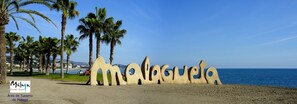 A beach with palm trees and a sign spelling 'Malaga'. - Holidays2Malaga Juan de Mena Apartments (Málaga)