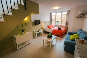 A modern living room with a sofa, a coffee table, a TV, and a staircase. - Holidays2Malaga Juan de Mena Apartments (Málaga)
