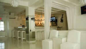 Una sala de estar moderna con un sofá blanco, una mesa de centro de vidrio y una zona de bar con taburetes.