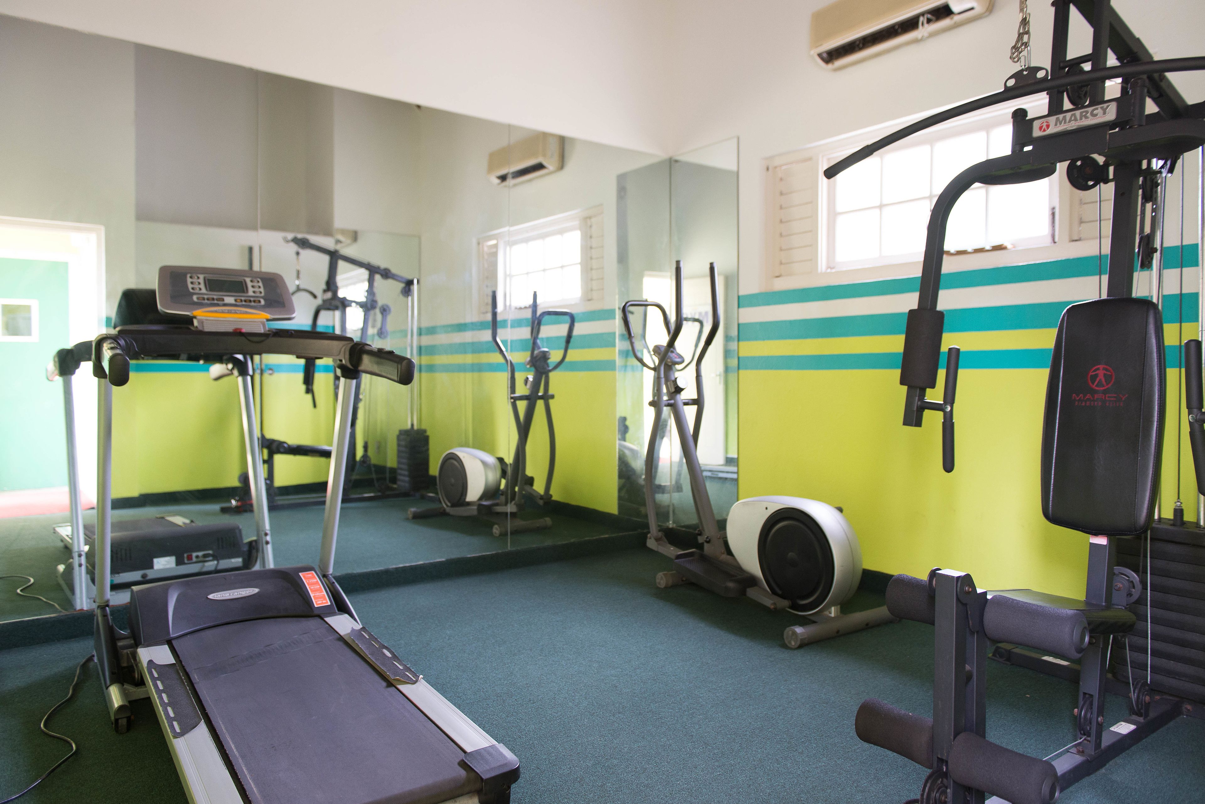 A gym with exercise equipment, a treadmill, and a mirrored wall.