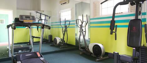 A gym with exercise equipment, a treadmill, and a mirrored wall.