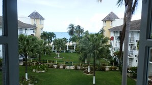 Vista de un resort con varias construcciones, palmeras y una playa al fondo.