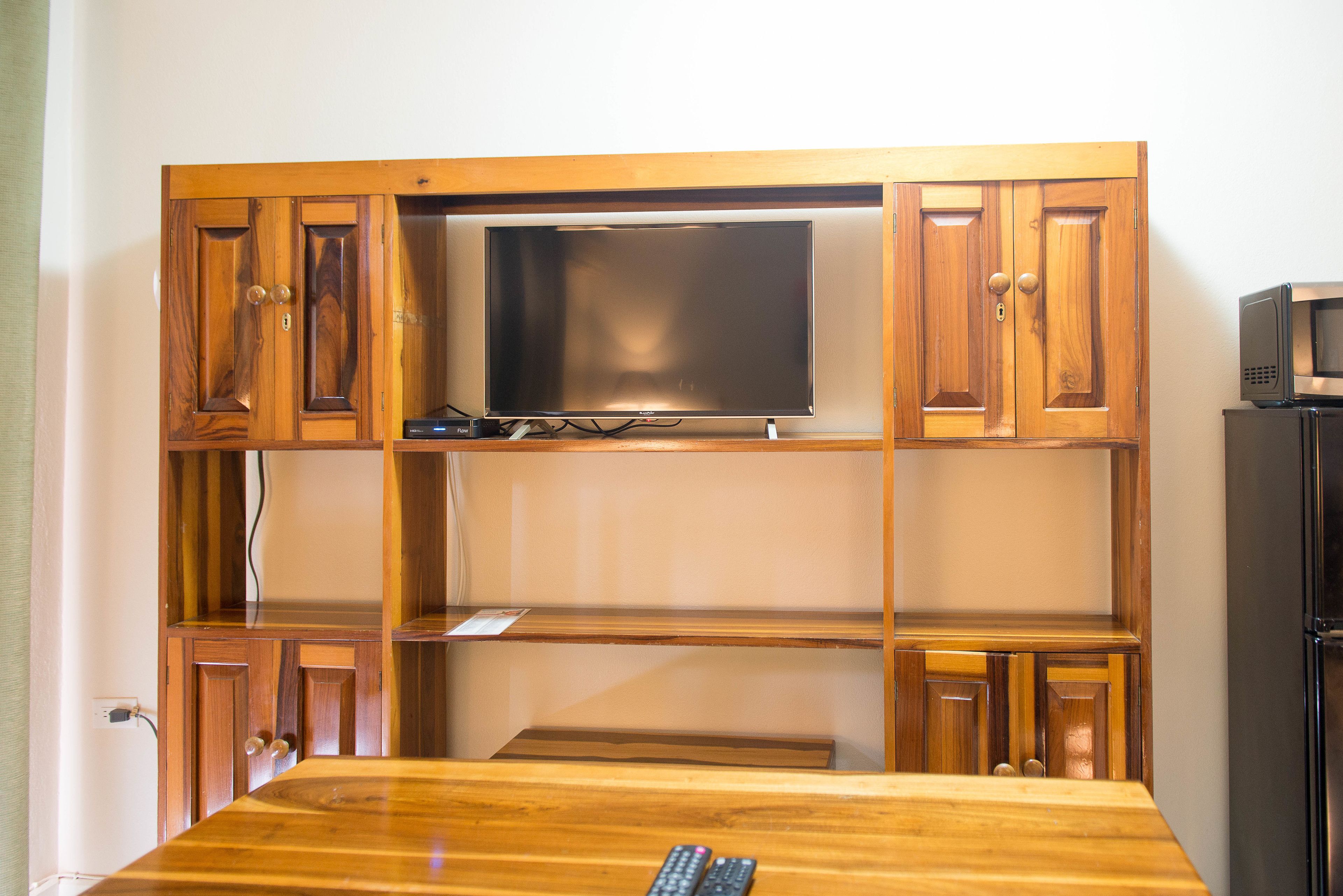 A wooden cabinet with a flat-screen TV mounted on the top shelf.