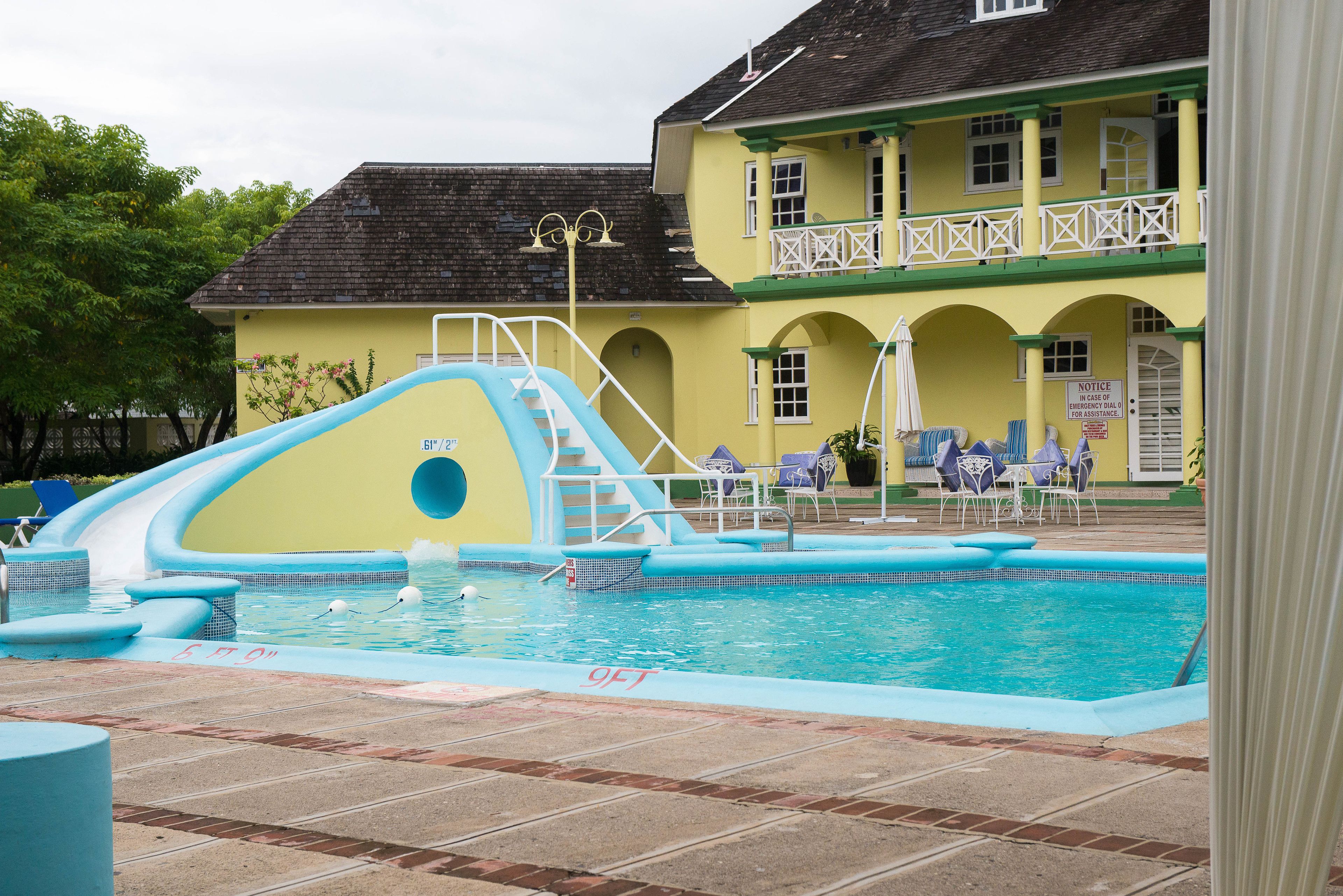 Ein Poolbereich mit Rutsche, Liegestühlen und einem Gebäude mit Balkon.