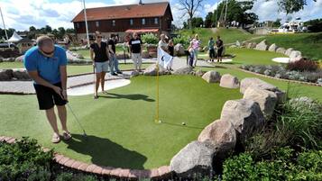 A miniature golf course with a putting green, a flag, and a brick border.