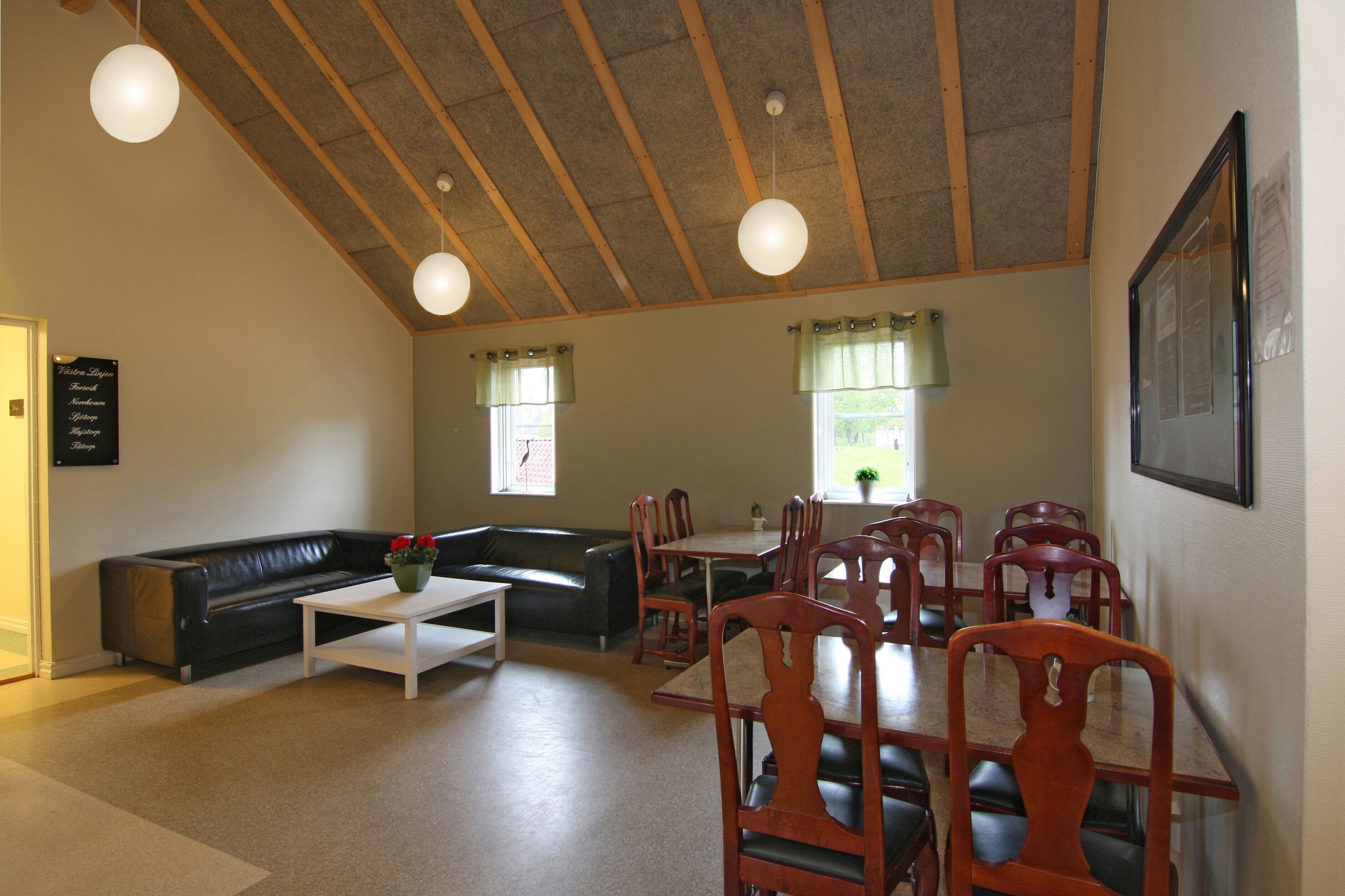 A dining area with a high ceiling, wooden beams, and a white table with chairs.