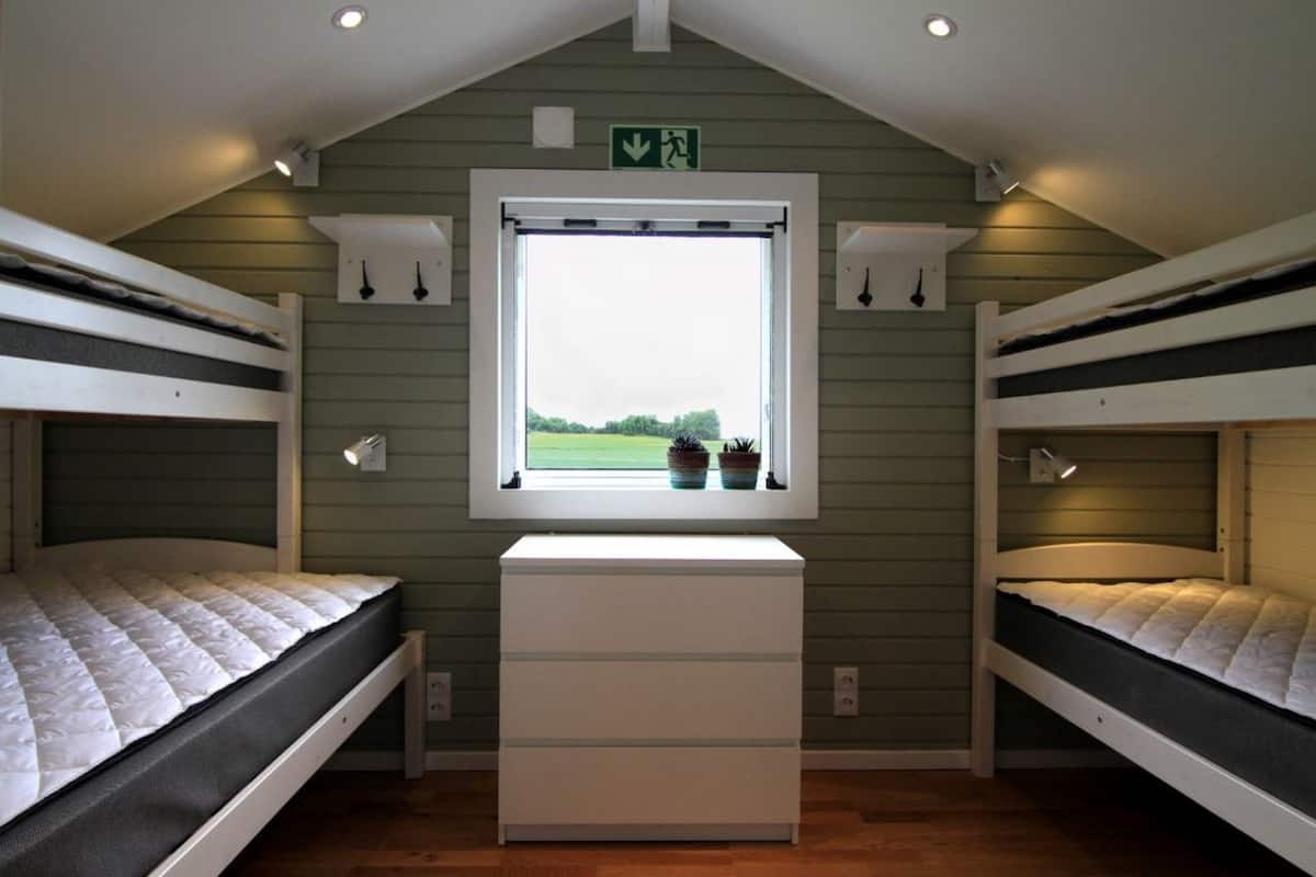 A bunk bed room with a window and a desk.