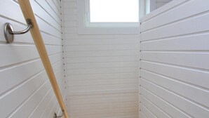 A narrow stairway with white paneling and a small window at the top.