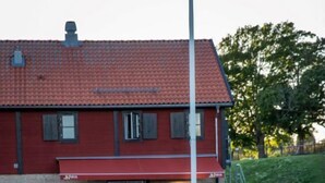 A red building with a tiled roof, a small garden with a pond, and a pathway leading to a door. - Bergs Slussar Vandrarhem & Stugor - Hostel (Vreta Kloster)