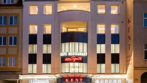 En moderne bygning med en restaurant kaldet 'Cafe Restaurant armSpitz' og et 'Kent' skilt på facaden.