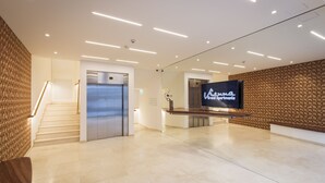 En moderne hotellobby med reception, trappe og elevator.