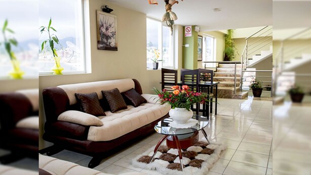 A living room with a sofa, a glass coffee table, and a rug. - Hotel Las Gardenias (Cuenca)