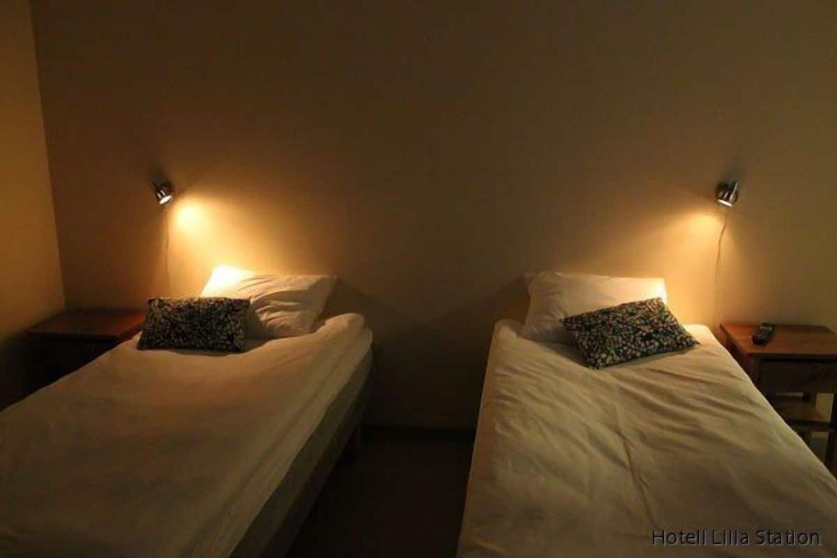 Two single beds with headboards, each with a bedside table and a lamp.