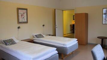 Une chambre d’hôtel avec deux lits simples, une petite table et une chaise.