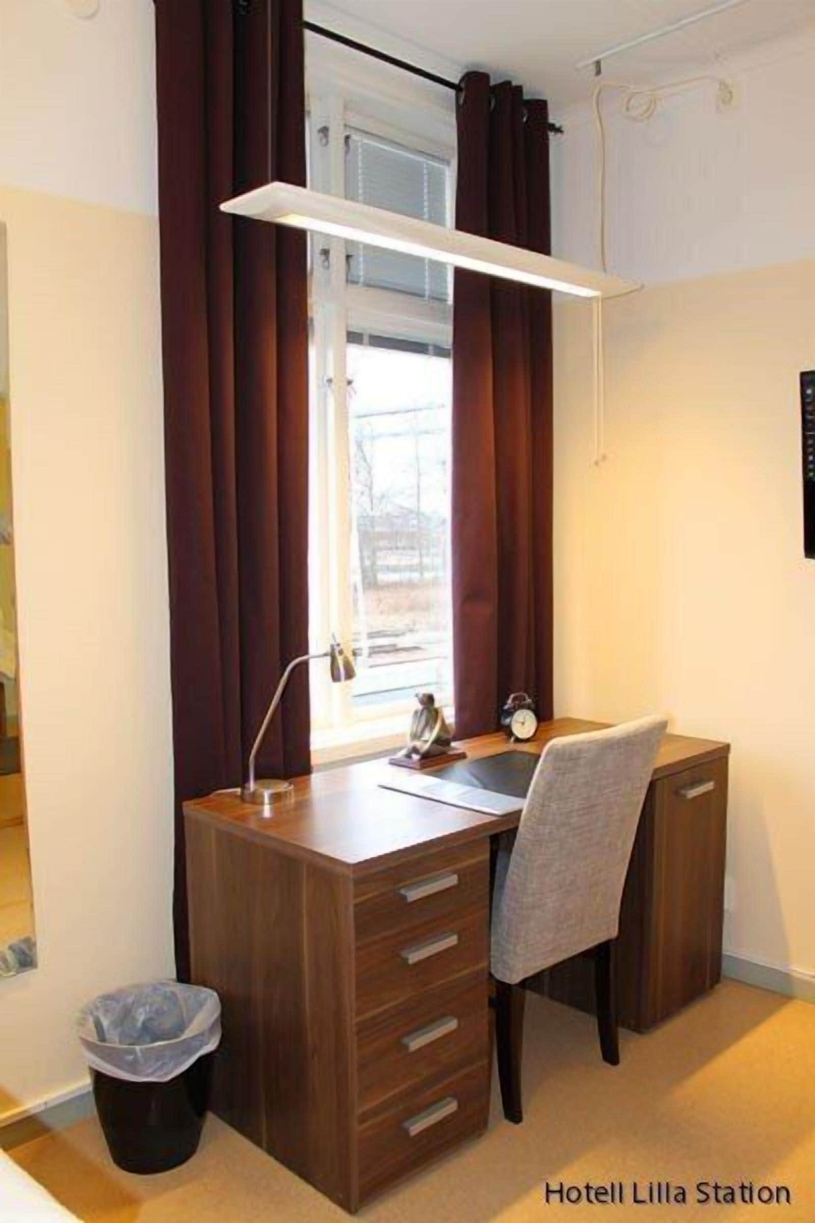 A compact office space with a desk, chair, and a small trash bin.
