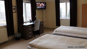 Une chambre d’hôtel avec un lit, un bureau, une chaise et un téléviseur.