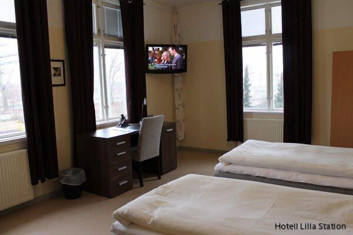 A hotel room with a bed, a desk, a chair, and a television.