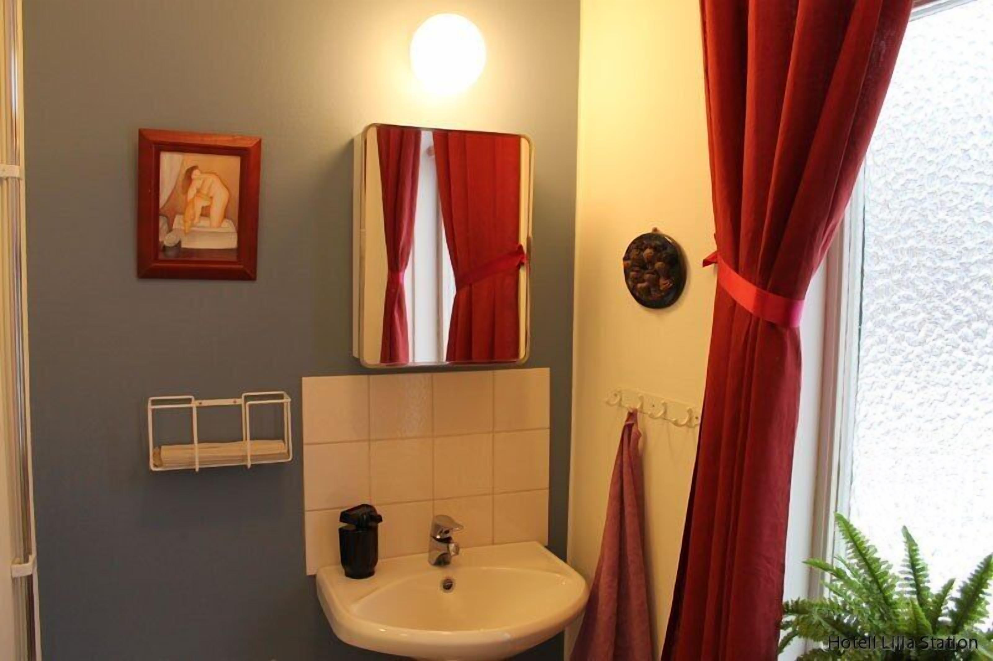 A bathroom with a sink, mirror, and red curtains.