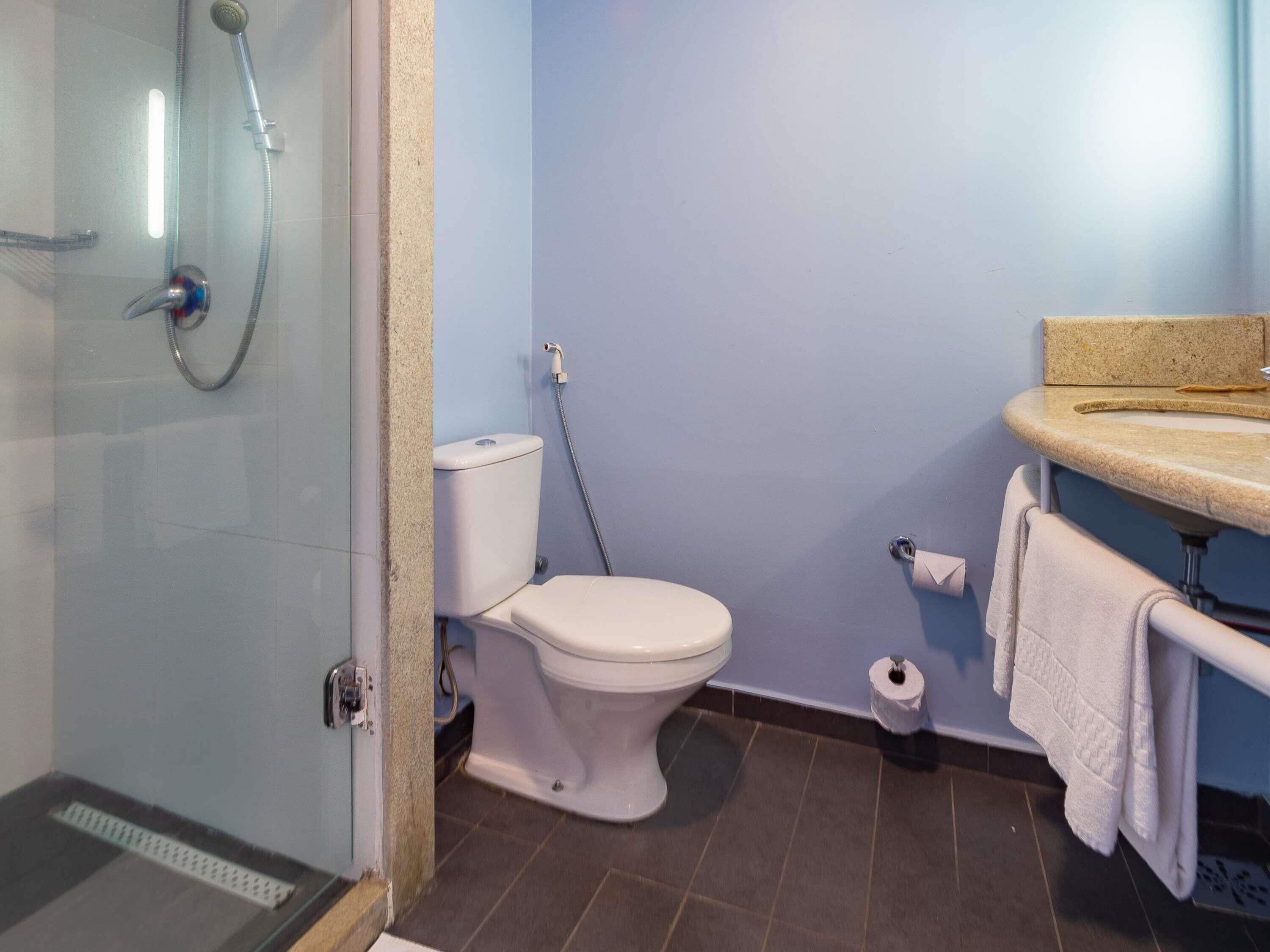 A bathroom with a toilet, shower, and sink.