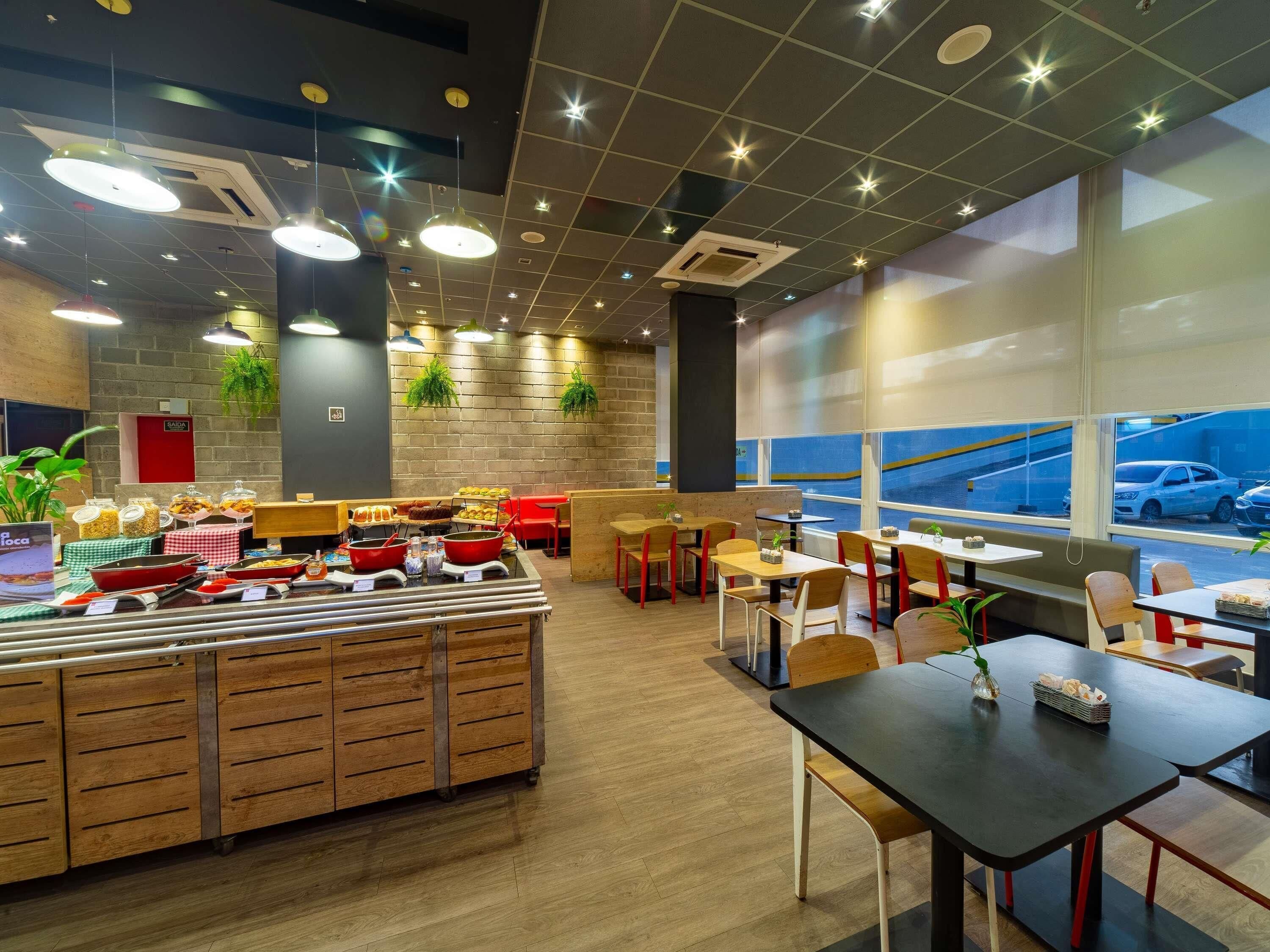 Een restaurant met een buffet, houten meubels en grote ramen.