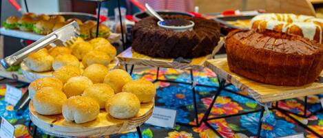 Un buffet proposant divers plats, notamment des petits pains, un gâteau au chocolat et une miche de pain.