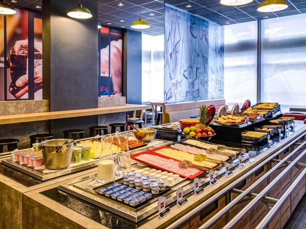A buffet with various food items, a milk dispenser, and a fruit display.