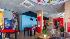 Een moderne lobby met een pooltafel, tafelvoetbal en een zithoek.