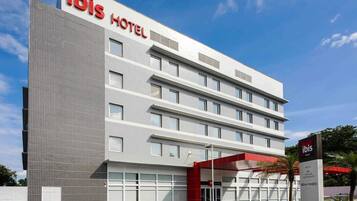 A modern ibis hotel with a tiled facade, multiple floors, and a prominent red entrance.