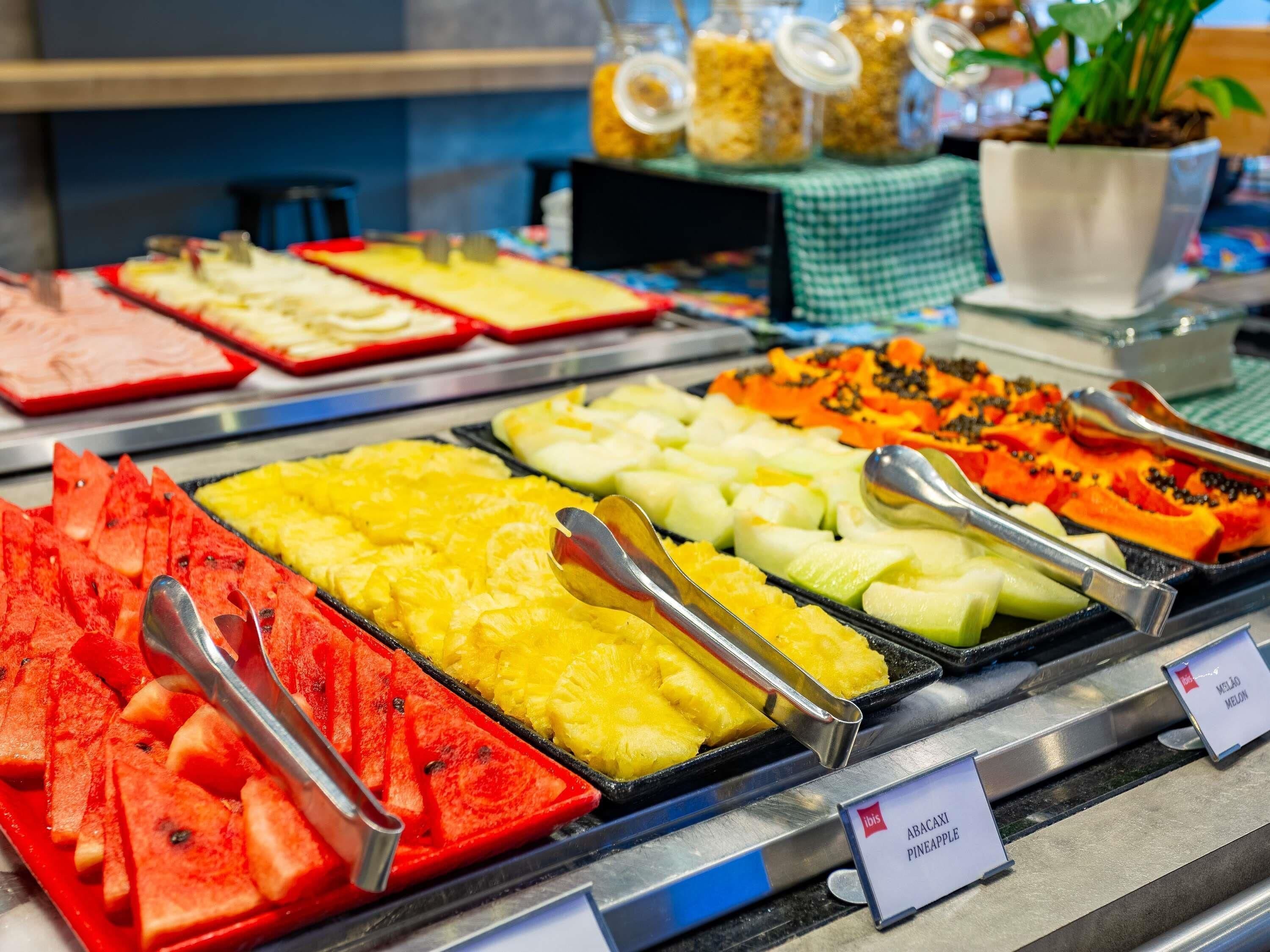 A buffet with various fruits and a sign indicating 'ABACAXI PINEAPPLE.'