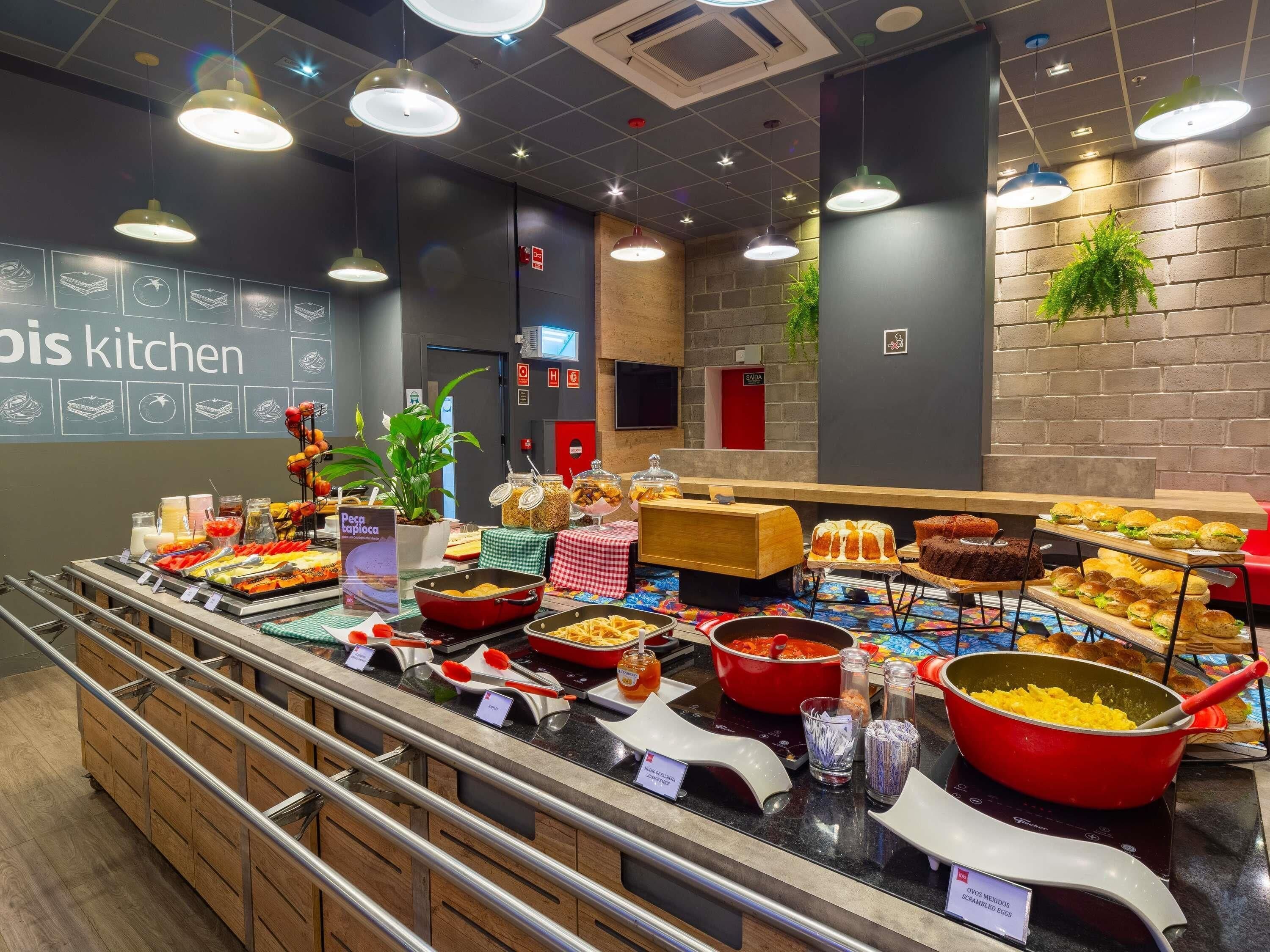 A buffet with various food options, a kitchen sign, and a brick wall.