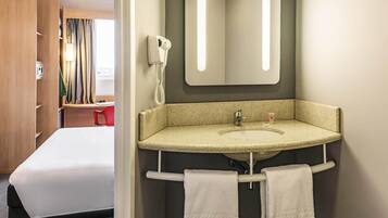 Een hotelbadkamer met een wastafel, spiegel, handdoekhouder en een telefoon.