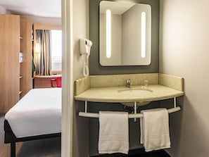 A hotel bathroom with a sink, mirror, towel rack, and a telephone.