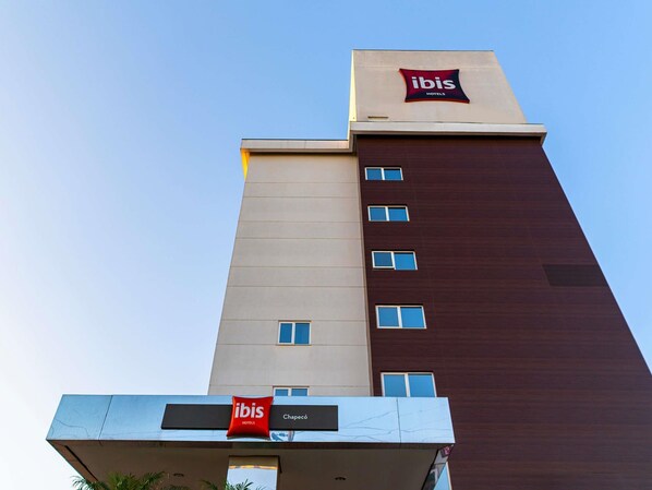 Ett hotell med modern design, med en tydlig skylt med texten ”ibis Hotels” högst upp och en skylt med texten ”Chapeco” på den nedre våningen.