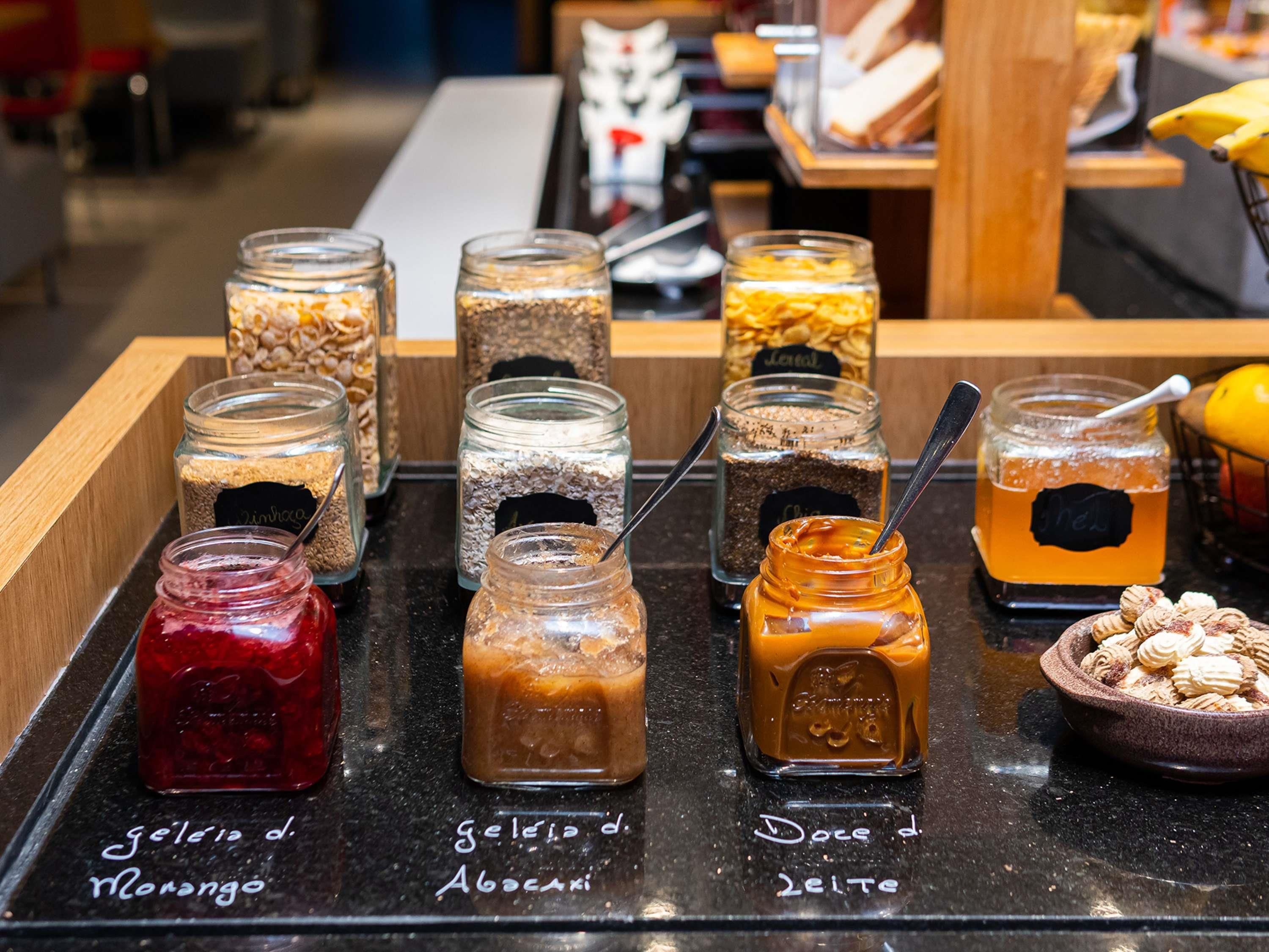 A selection of jars with various spreads and a bowl of nuts on a counter.