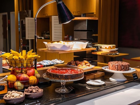 A buffet with various food items, including fruits, pastries, and desserts.. ibis Chapeco