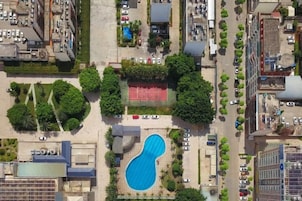 Vista aérea de un área residencial con piscina rodeada de árboles y una cancha de tenis.