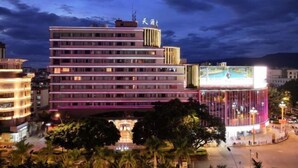 A multi-story hotel with a modern design, featuring a prominent glass facade and a rooftop sign. - WEISELECT MengZi Tian Yuan Hotel (Honghe)