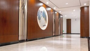 A modern hotel lobby with a polished marble floor, wooden paneling, and a circular artwork on the wall. - WEISELECT MengZi Tian Yuan Hotel (Honghe)