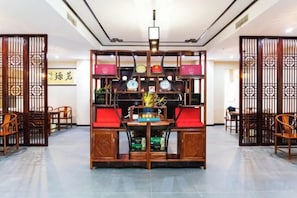 Un área de estar de estilo tradicional con una mesa central, rodeada de sillas y un separador decorativo.