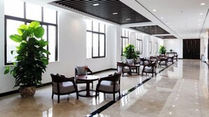 A modern hotel lobby with a long reception desk, multiple seating areas, and large windows providing natural light. - WEISELECT MengZi Tian Yuan Hotel (Honghe)