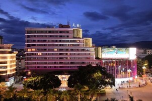 Un hotel de varios pisos con un cartel llamativo y un gran anuncio iluminado.