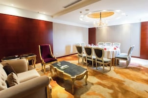 Habitación de hotel con comedor, sofá, mesa de centro y candelabro.